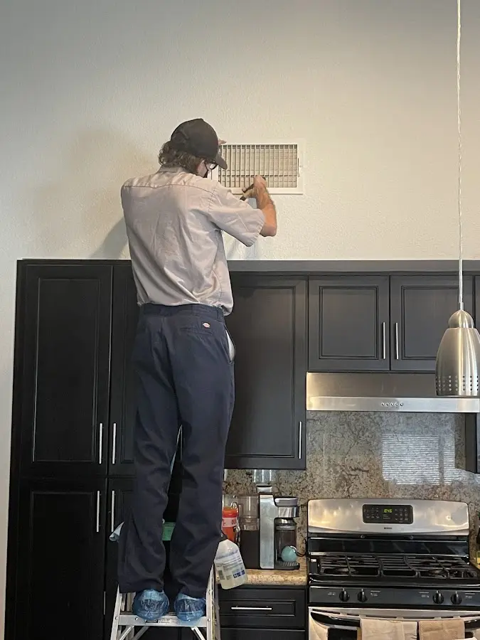 Technician inspecting an air vent during HVAC service in Sunbury